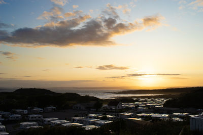 High angle view of townscape by sea against sky during sunset