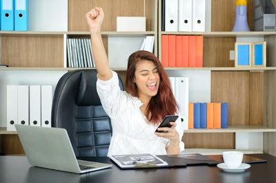 Young woman using phone while sitting on table