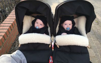 Portrait of smiling boys in strollers on footpath