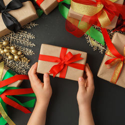 Flat lay of kids hands holding gift wrapped stylish black friday, christmas, happy 2022 new year