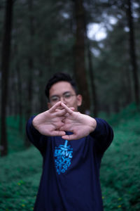 Portrait of young man stretching hands at forest