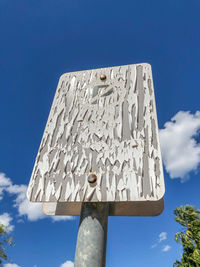 Low angle view of text on pole against blue sky