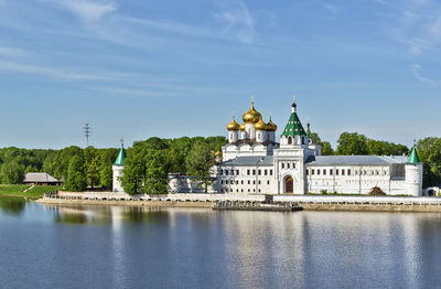 View of temple by river against sky