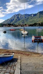 Sailboats moored on lake against sky