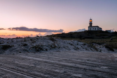 View of lighthouse and buildings against sky during sunset