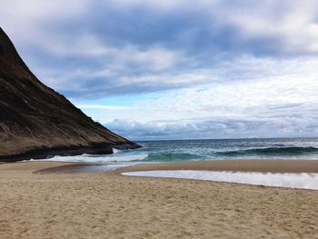 View of calm beach against clouds