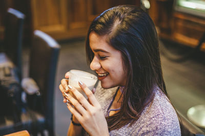 Close-up of a young woman drinking glass at restaurant