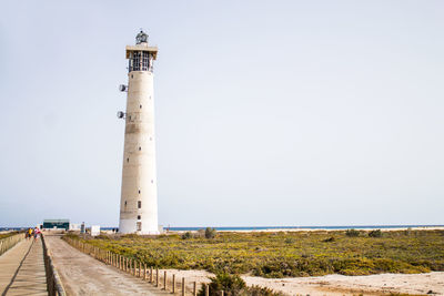 Lighthouse amidst land against clear sky