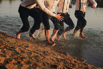 Low section of people walking on beach