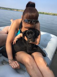 Midsection of woman with dog sitting in water