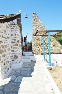 Woman ringing bell in old house on sunny day