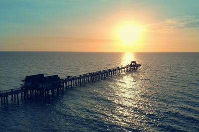 Naples beach and fishing pier at sunset, florida. dark silhouette of a pier over the water at sunset