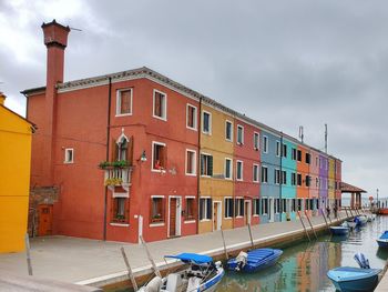 Buildings by canal against sky in city