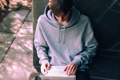 Full length of teenage girl sitting on mobile phone