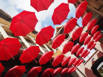 Low angle tilt image of red umbrellas hanging in city