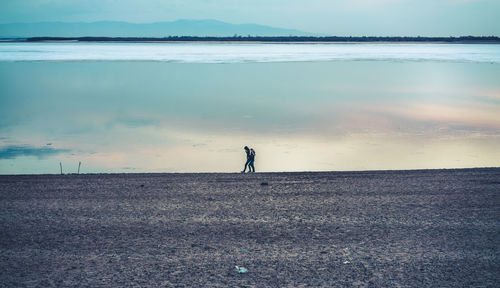 Man standing on beach against sky during sunset