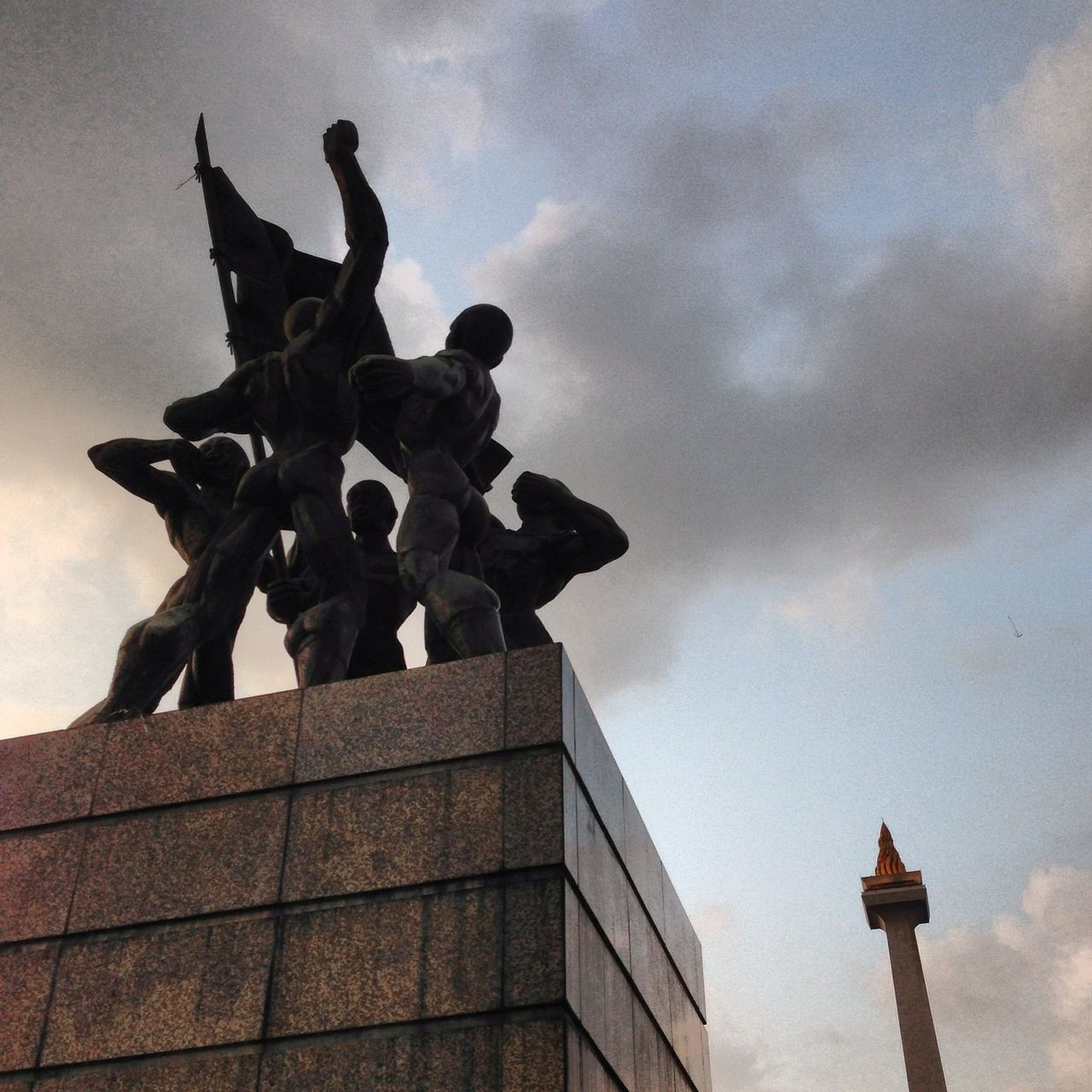 low angle view, sky, statue, sculpture, human representation, cloud - sky, built structure, architecture, art, art and craft, building exterior, cloudy, creativity, cloud, silhouette, outdoors, no people, animal representation, history