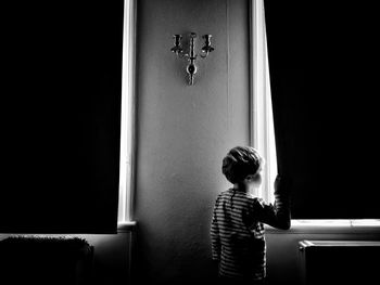Boy looking through window at home