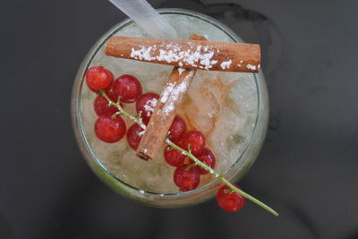 Directly above shot of drink with cherries and cinnamons on table