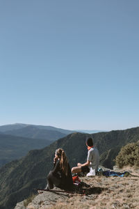 Girl and boy in the mountains watching the scenery while resting