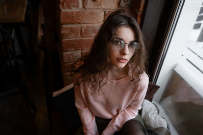 Portrait of young woman sitting by window