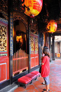 Rear view of girl standing against red wall