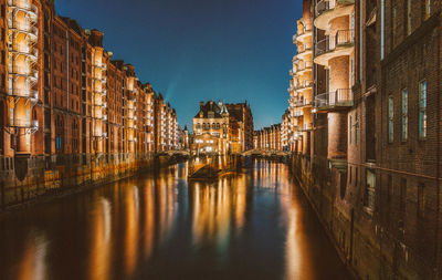 Bridge over canal amidst buildings against sky in city