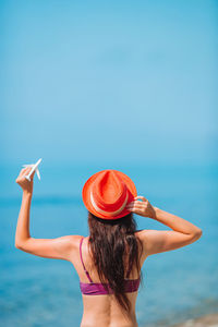 Rear view of woman walking in sea against sky