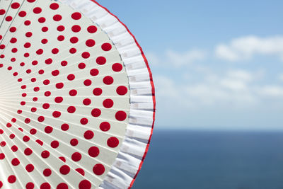 Close-up of red umbrella at beach against sky