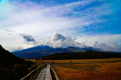 Scenic view of road leading towards mountains against sky
