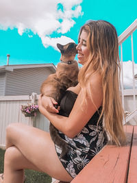 Side view of smiling woman holding cat