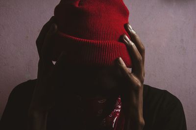 Portrait of man holding red hat against wall