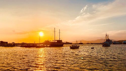 Sailboats in sea against sky during sunset