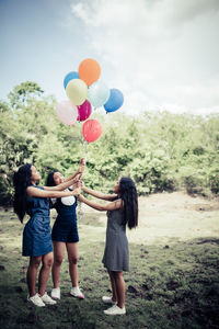 Rear view of two women standing on balloons