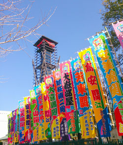 Low angle view of lanterns hanging by building against clear blue sky