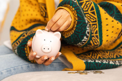 Midsection of woman holding piggy bank on table