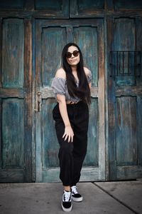 Portrait of young woman standing against door