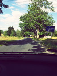 Road by trees seen through car windshield