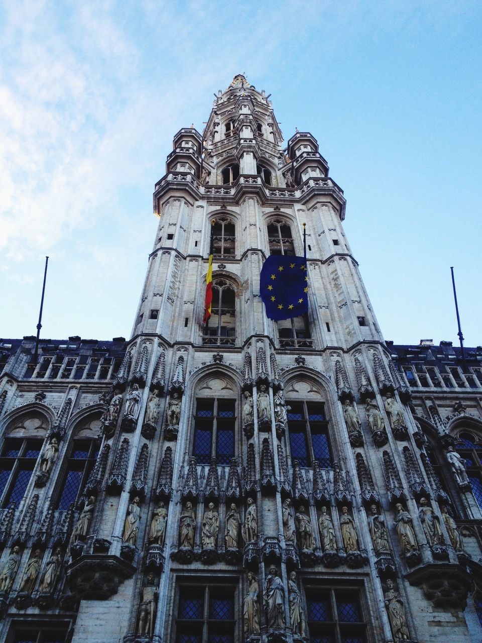 low angle view, architecture, building exterior, built structure, religion, church, place of worship, sky, cathedral, spirituality, city, blue, window, tower, day, clock tower, history, travel destinations