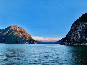 Scenic view of sea and mountains against blue sky