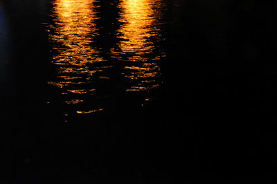 Reflection of silhouette trees in lake at night