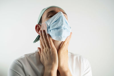 Portrait of person covering face against white background