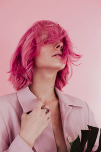 Close-up of young woman with dyed hair against colored background