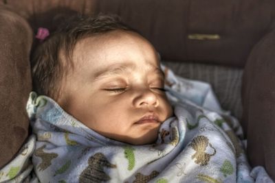 Sunlight falling on baby sleeping amidst pillows on bed