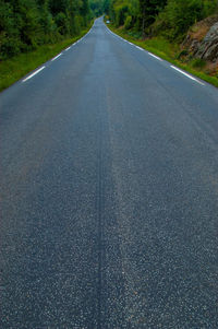 View of a long, wet road with white stripes on the sides
