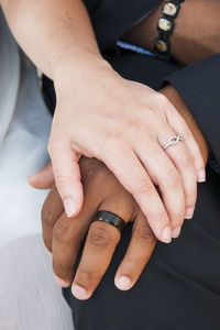 Interracial couple holding hands with wedding rings