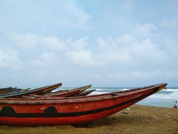 Boat moored on beach against sky