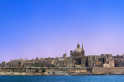 View of buildings in city against clear blue sky