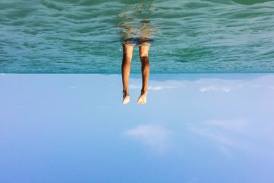 Tilt image of man swimming in sea against sky