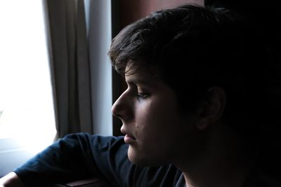 Portrait of teenage boy looking away at home